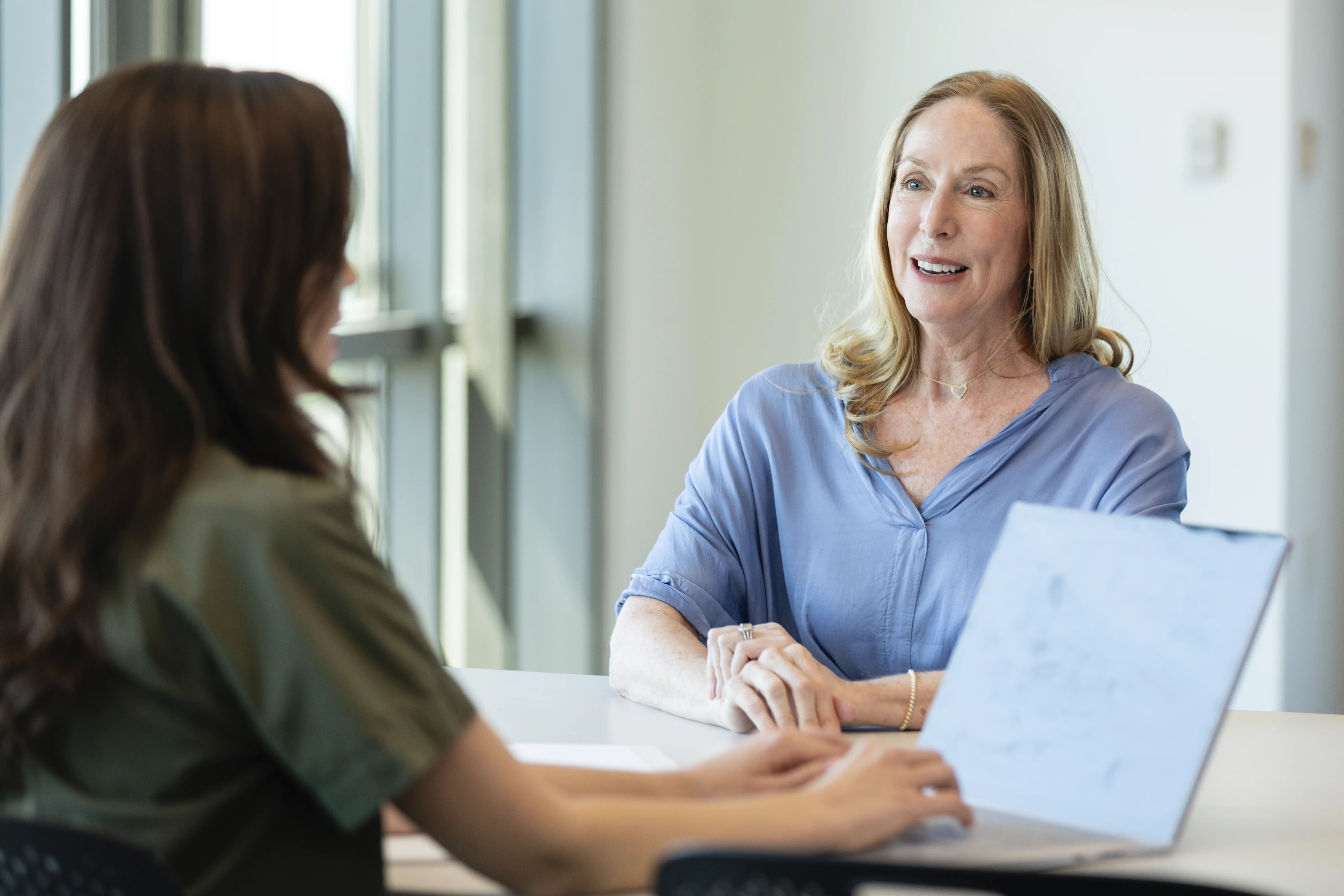 a middle aged woman talking to a female advisor at a counter