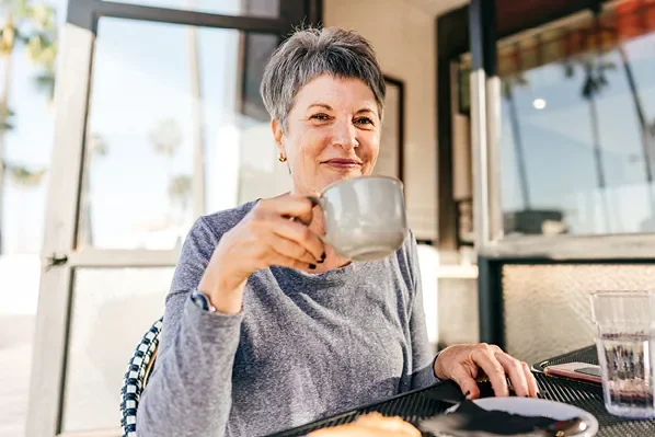 middle aged woman with short hair smiling and holding a mug