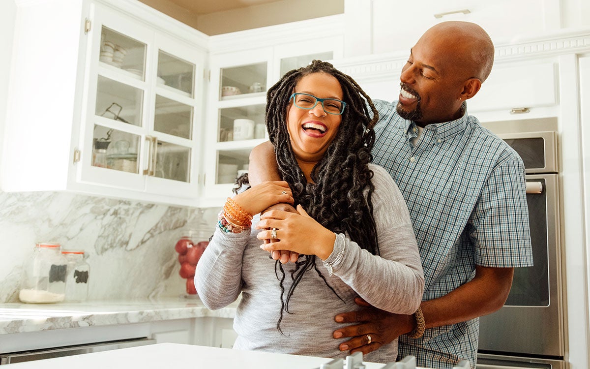 Middle-aged couple hugging and smiling in their kitchen
