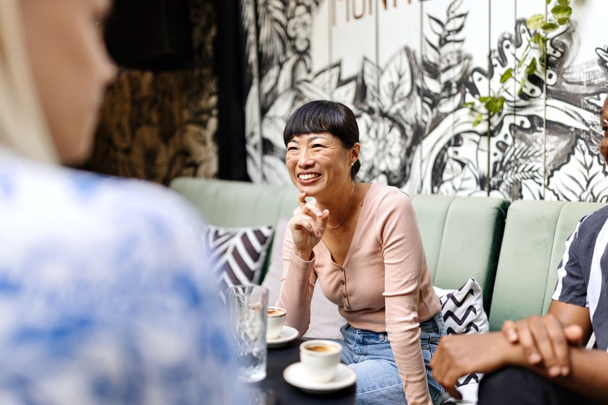 A person sitting at a café table enjoying a drink during a casual conversation.Provide your feedback on BizChat