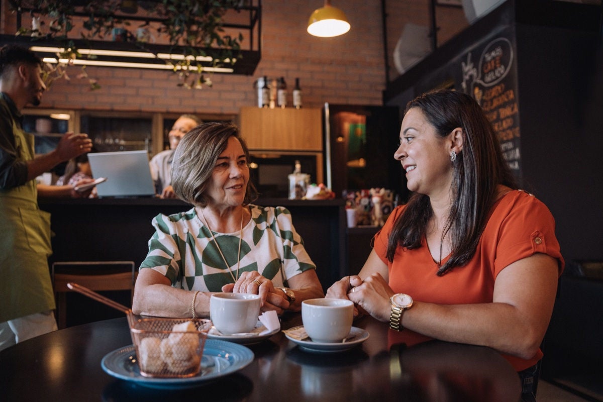 Two senior women enjoying coffee and conversation at a cafe