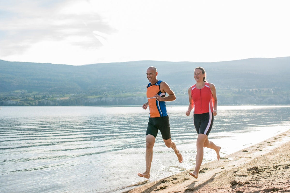 Man and woman running on a lakeside beach