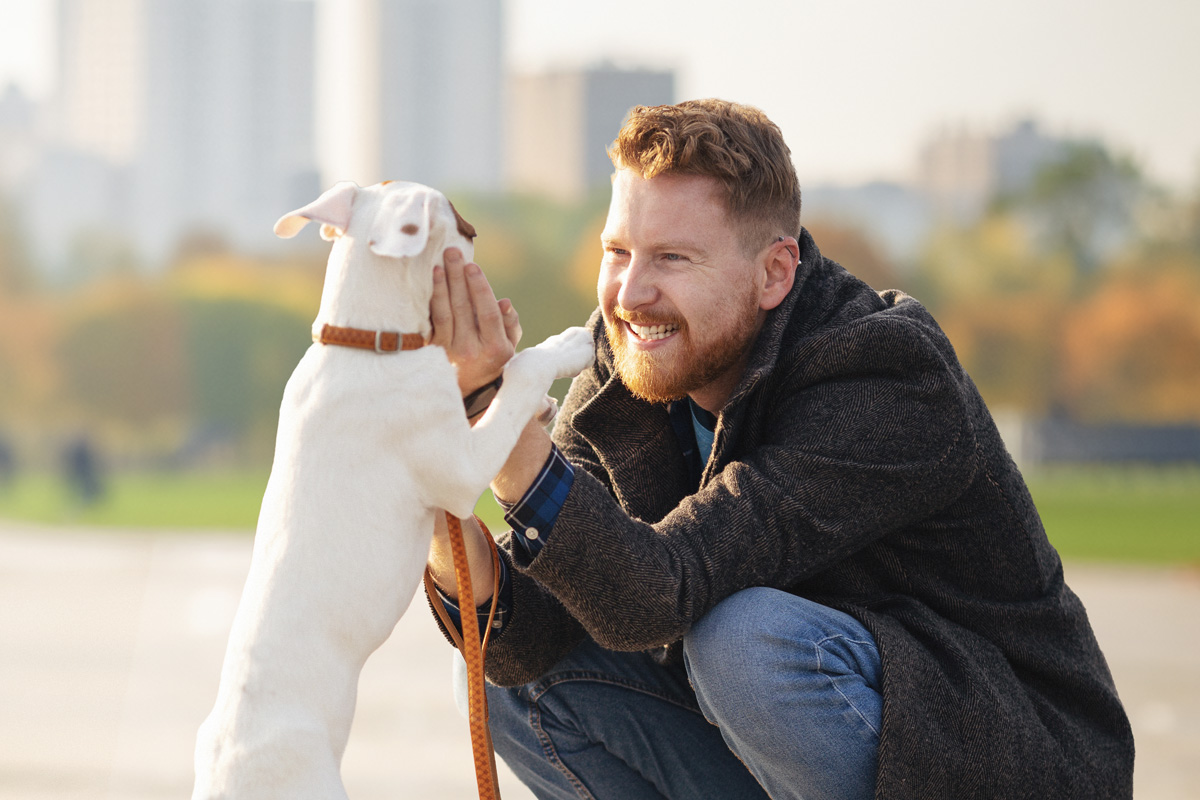 A man crouched down playing with his dog