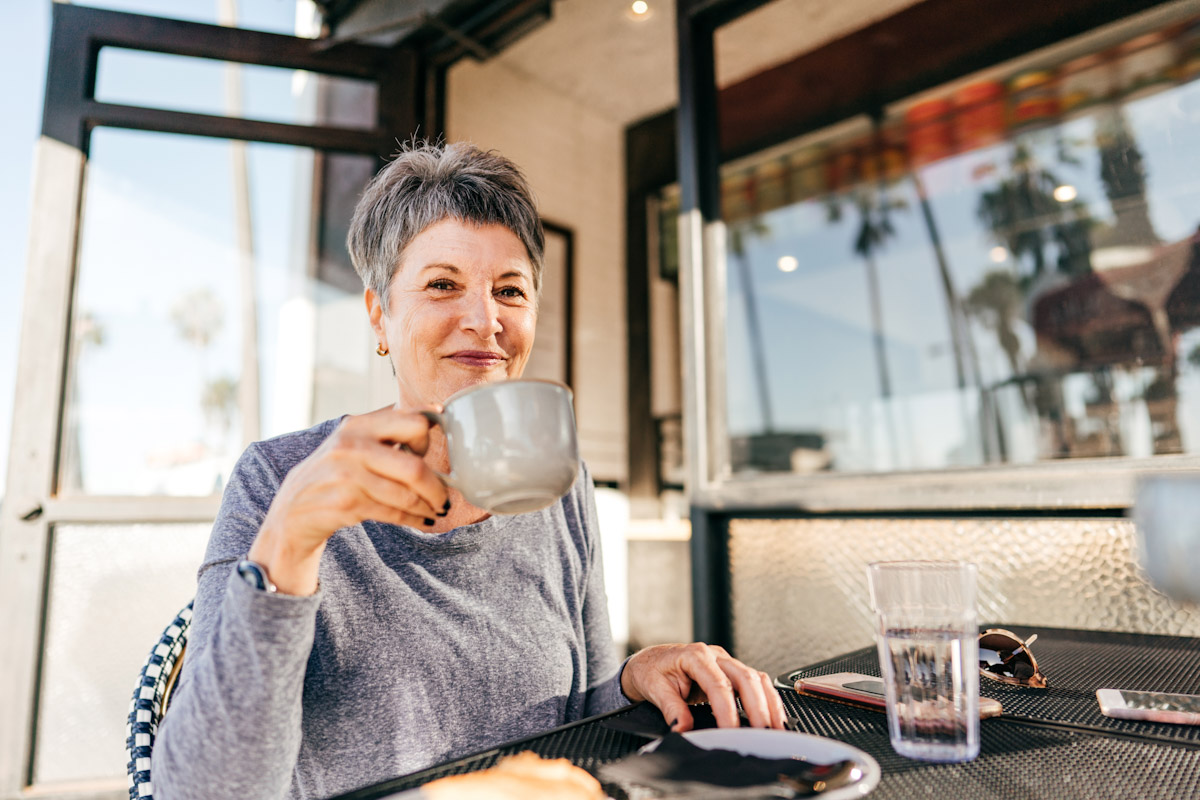 A woman seated at a dining table holding a mug